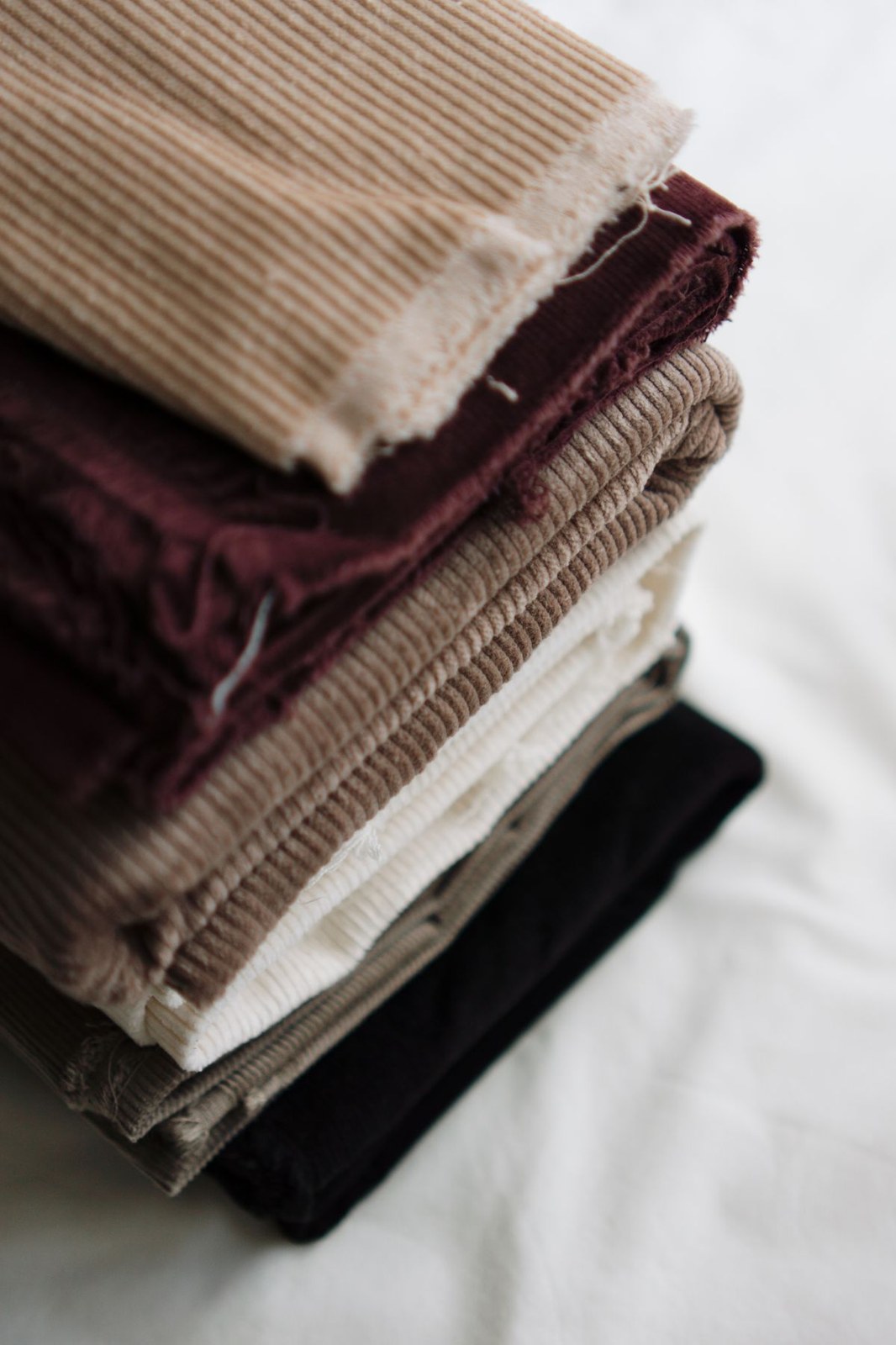 Stack of corduroy fabric swatches in tan brown and black for corduroy overalls