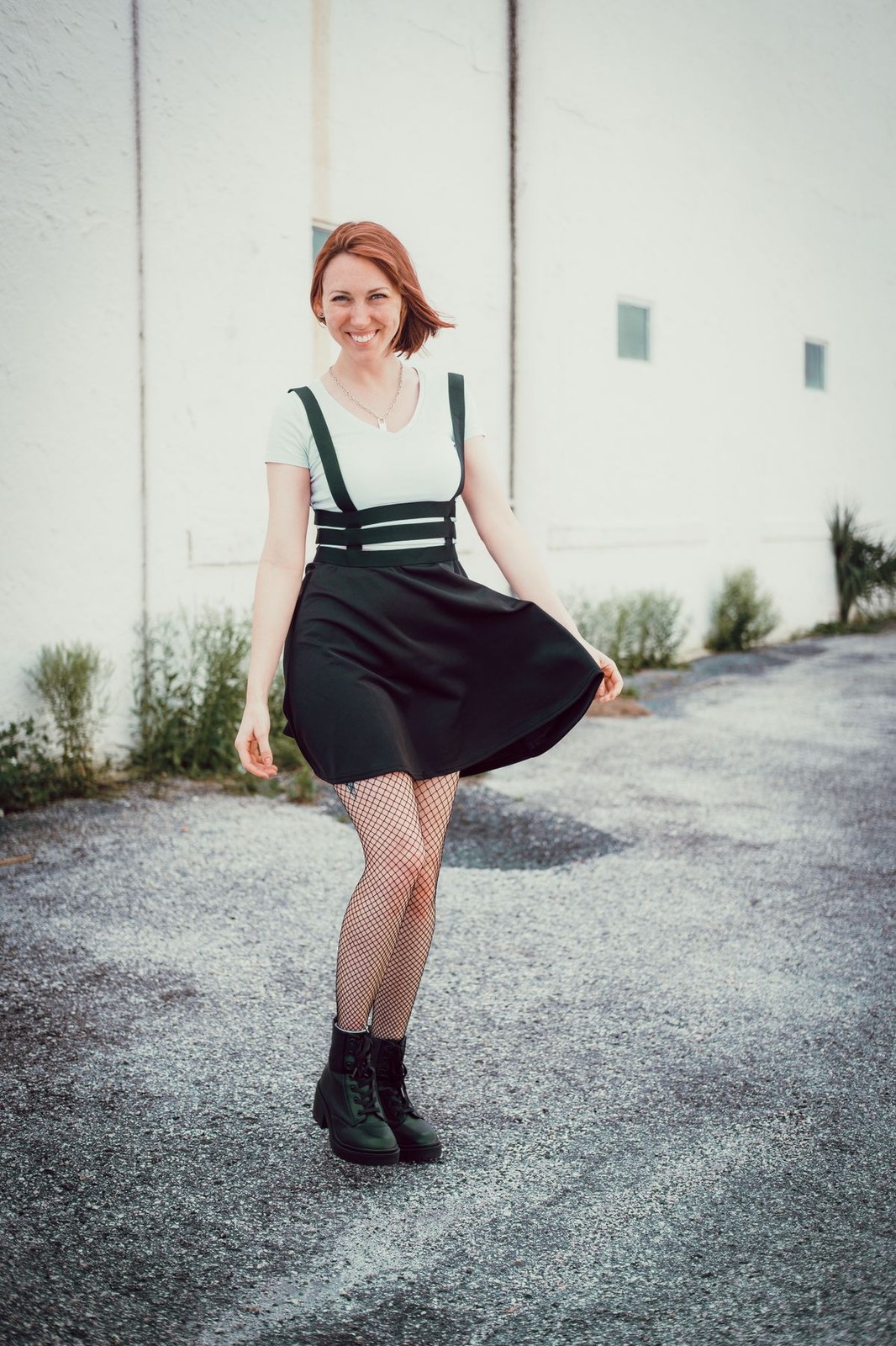 Plus size overall mini dress worn with tights and boots on a bright street
