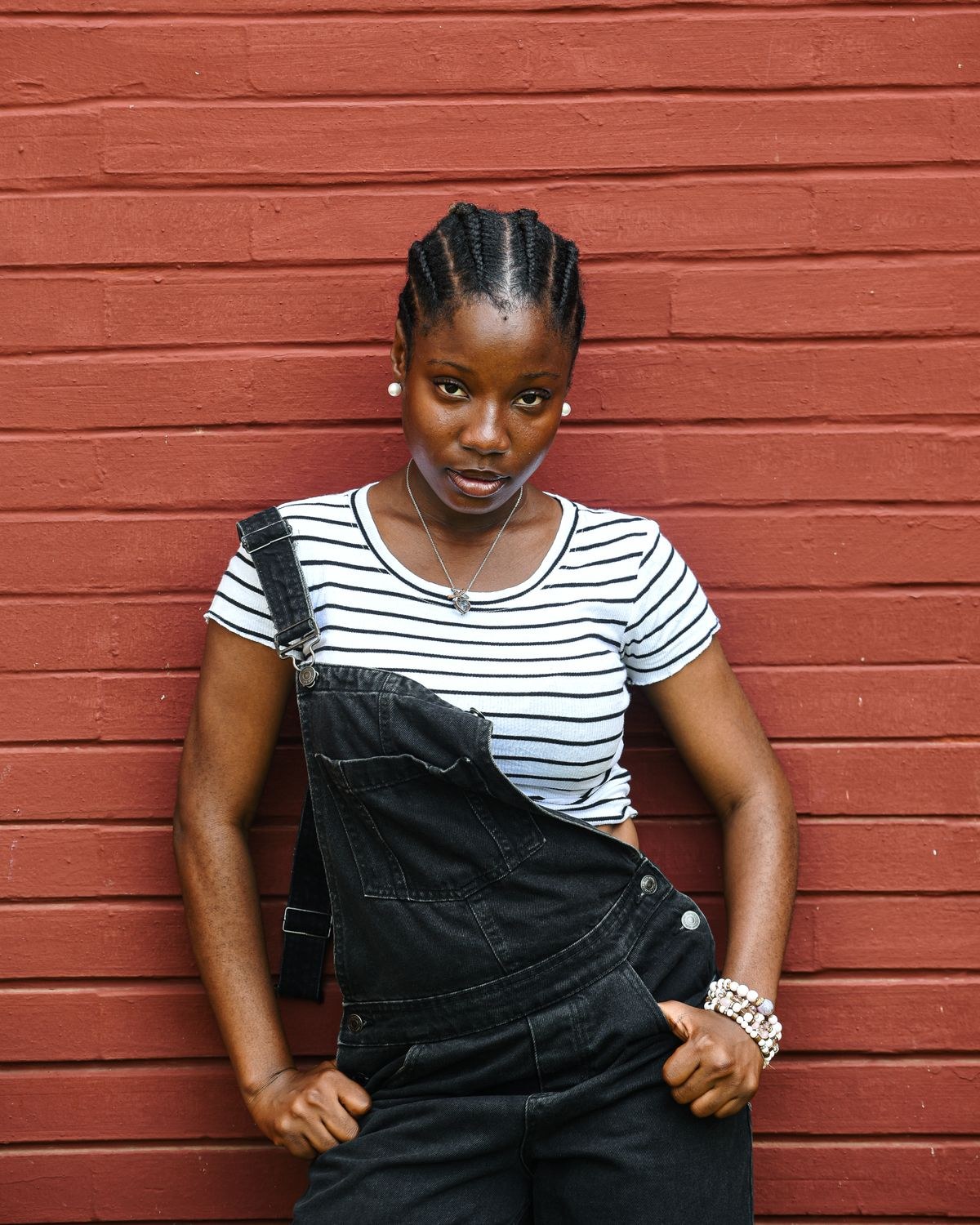Plus size overalls on a fuller figure with black denim bib overalls over a striped tee
