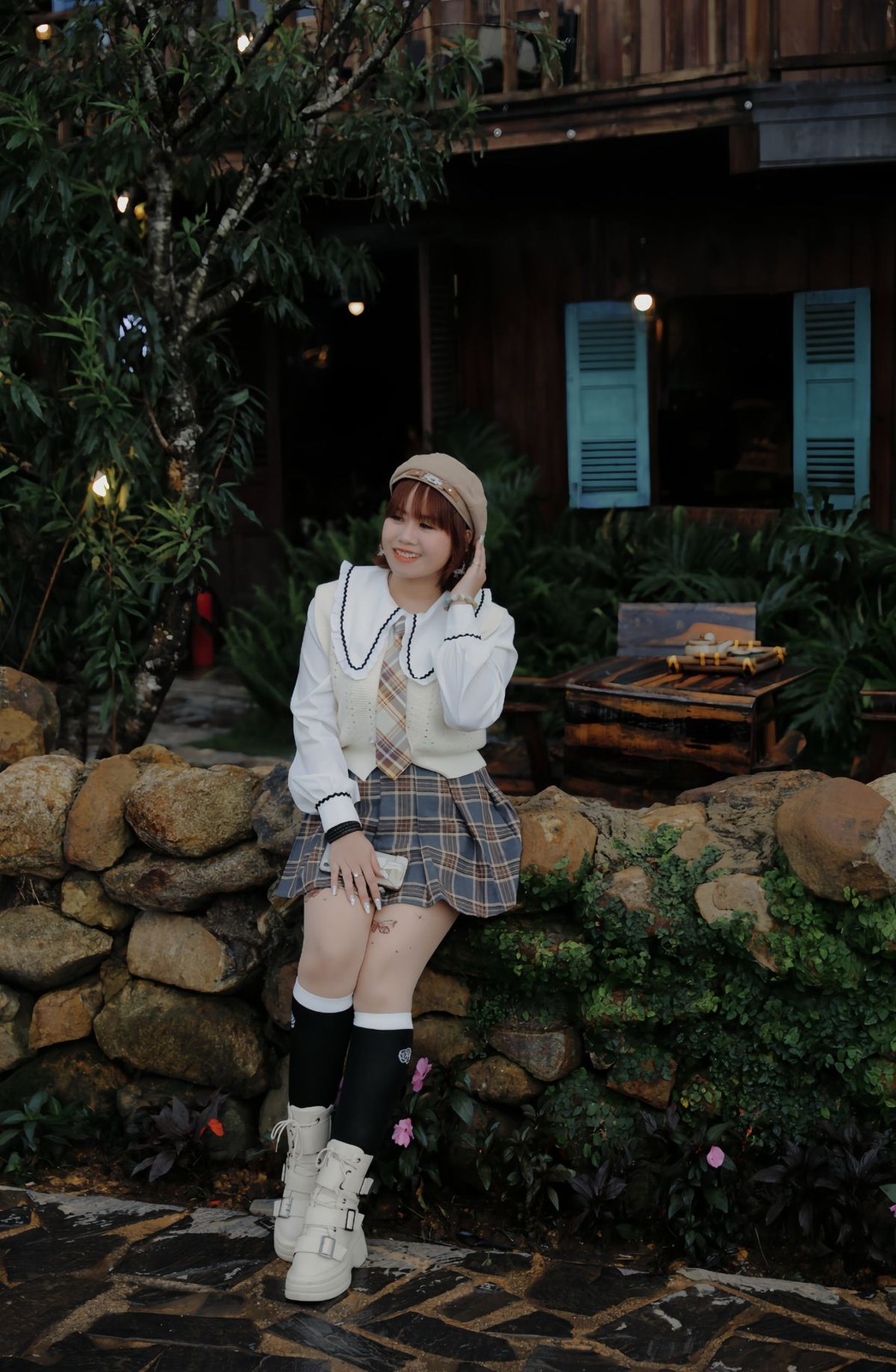 Knee high slouch socks styled with a plaid skirt and white boots in an autumn scene