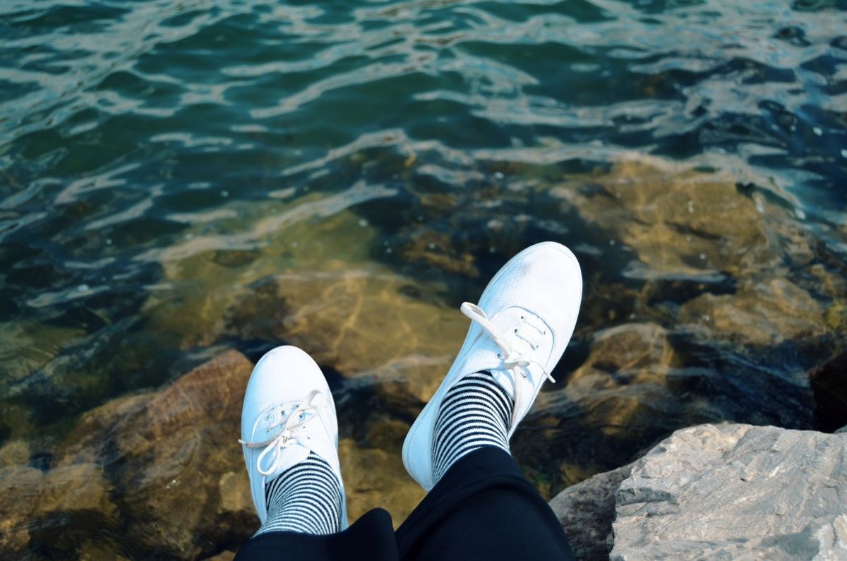 Black and white striped socks with white sneakers by the water for striped sock packs